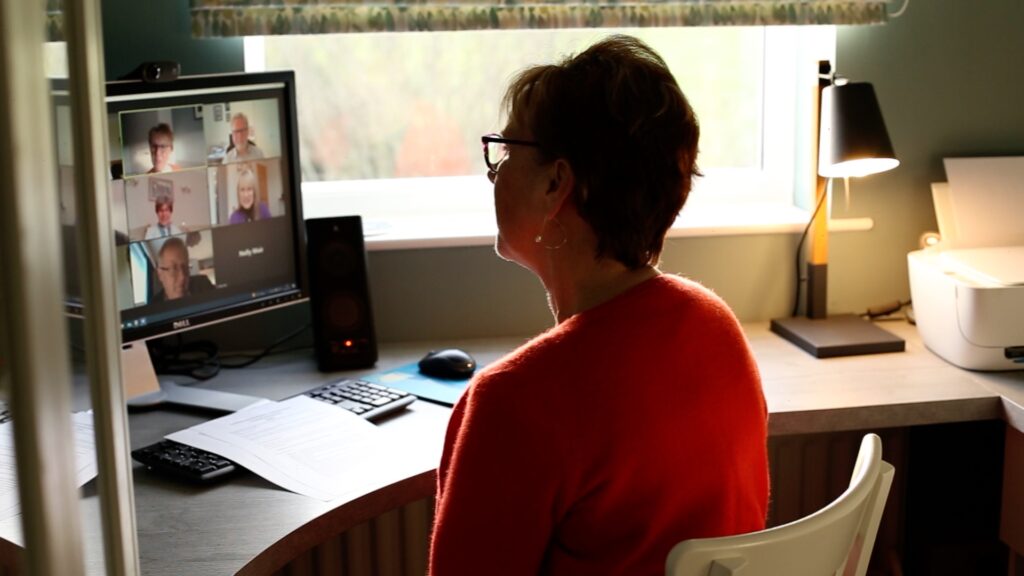 A lady sat at a screen taking part in an on line meeting