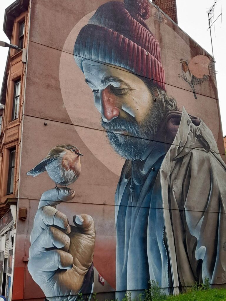 A street mural of a bearded man with ROBIN, TH PICTURE COVERS THE WHOLE OF A TENEMENT BLOCK END WALL.